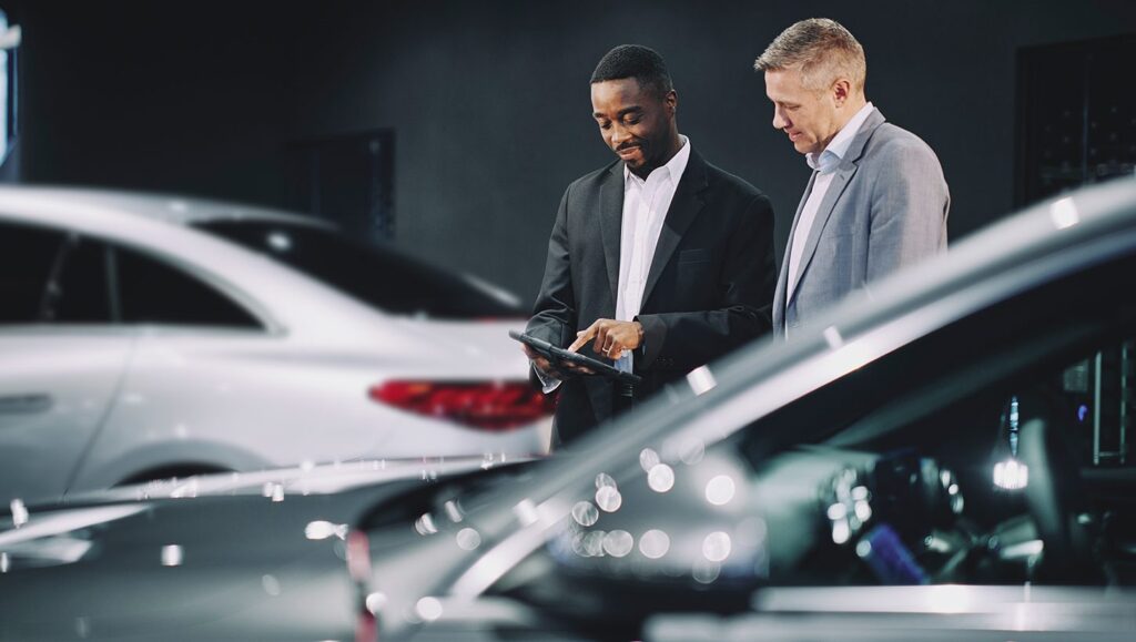 A dealership salesman showing a prospective customer the tablet while walking through the car dealership
