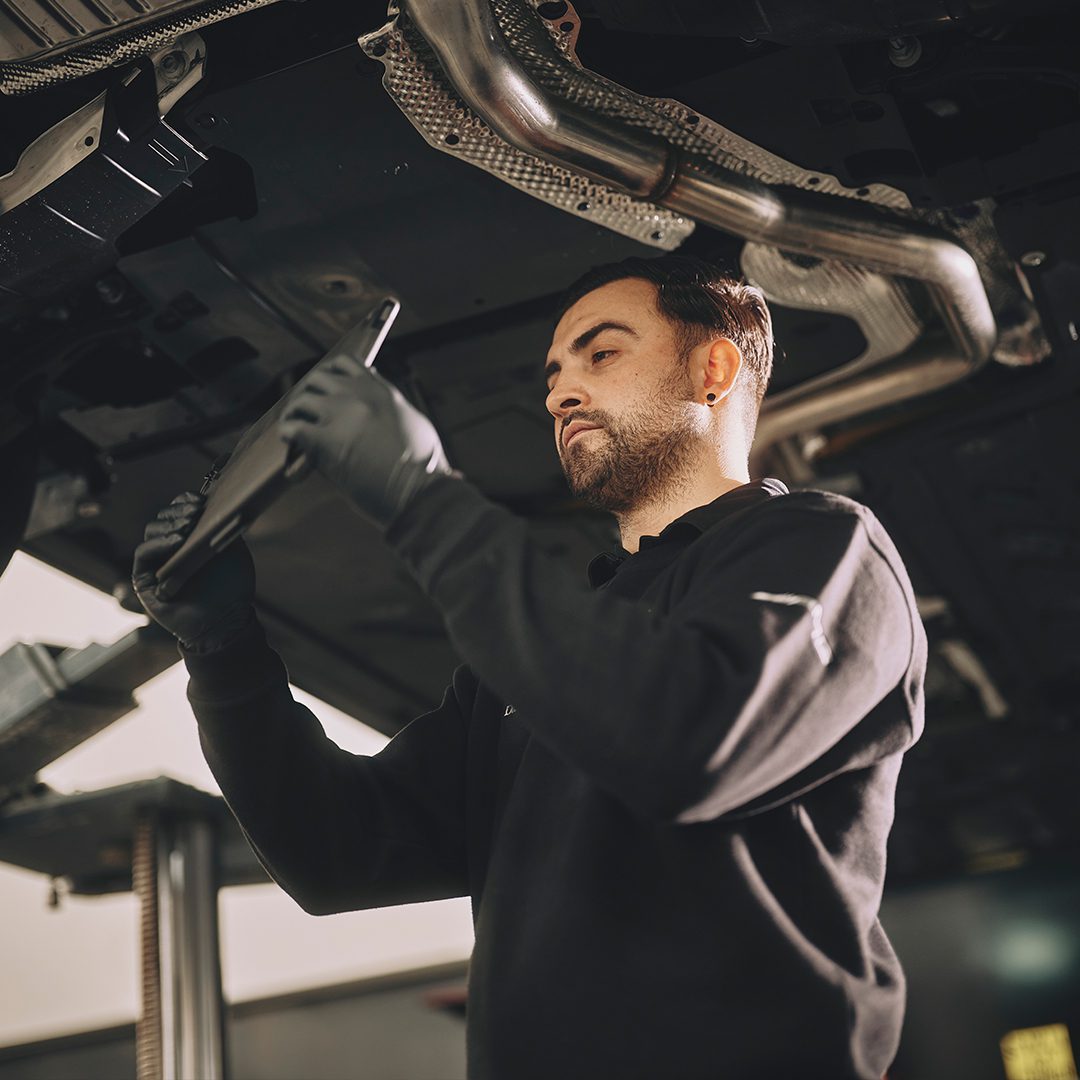 A technician using their tablet to inspect the car and record videos, all within the Pinewood system